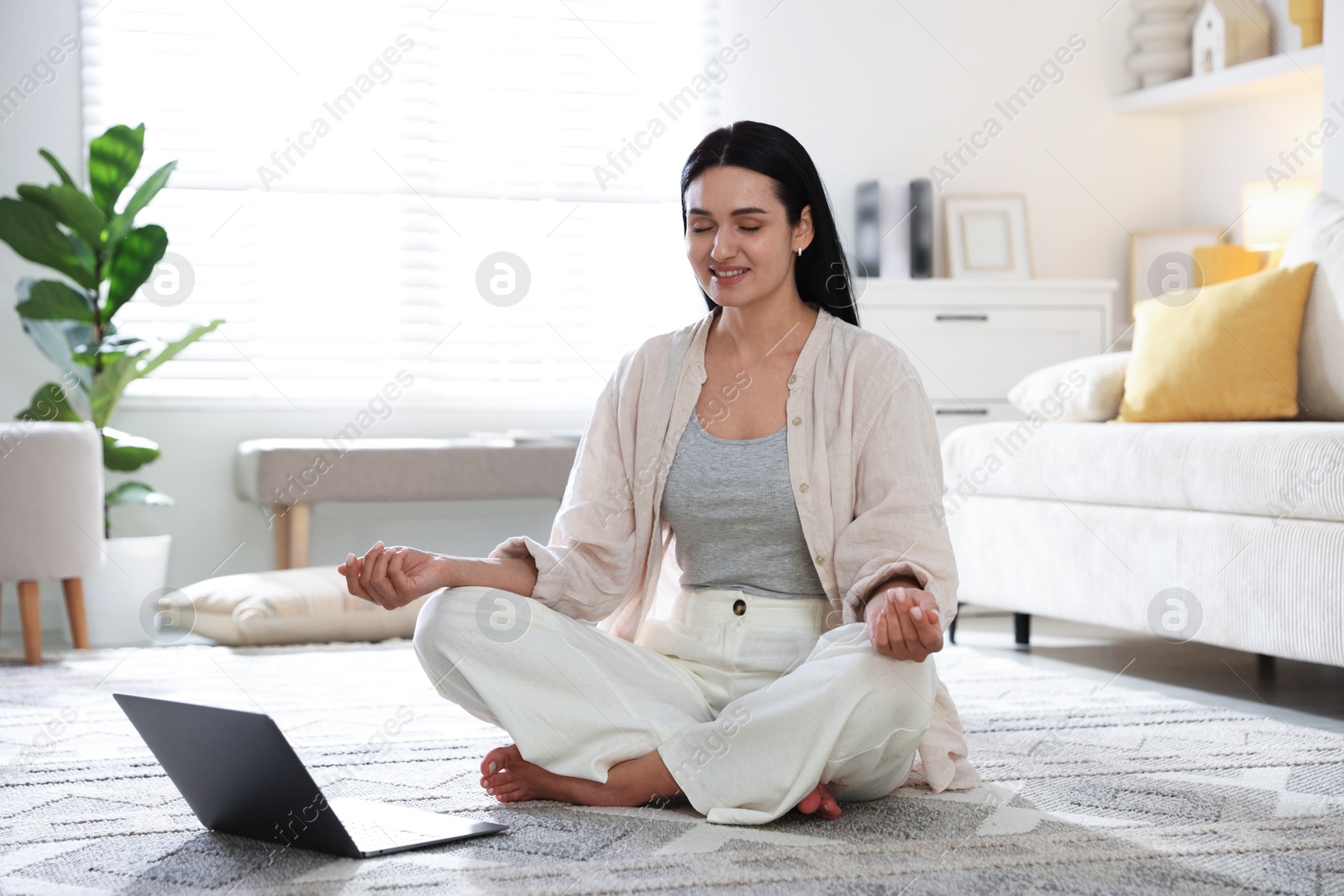 Photo of Woman with laptop meditating on floor at home