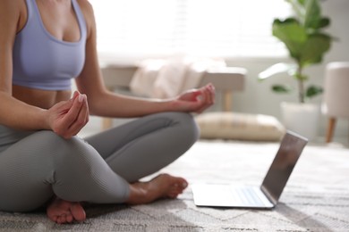 Woman with laptop meditating on floor at home, closeup