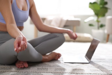 Photo of Woman with laptop meditating on floor at home, closeup