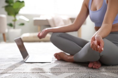 Photo of Woman with laptop meditating on floor at home, closeup