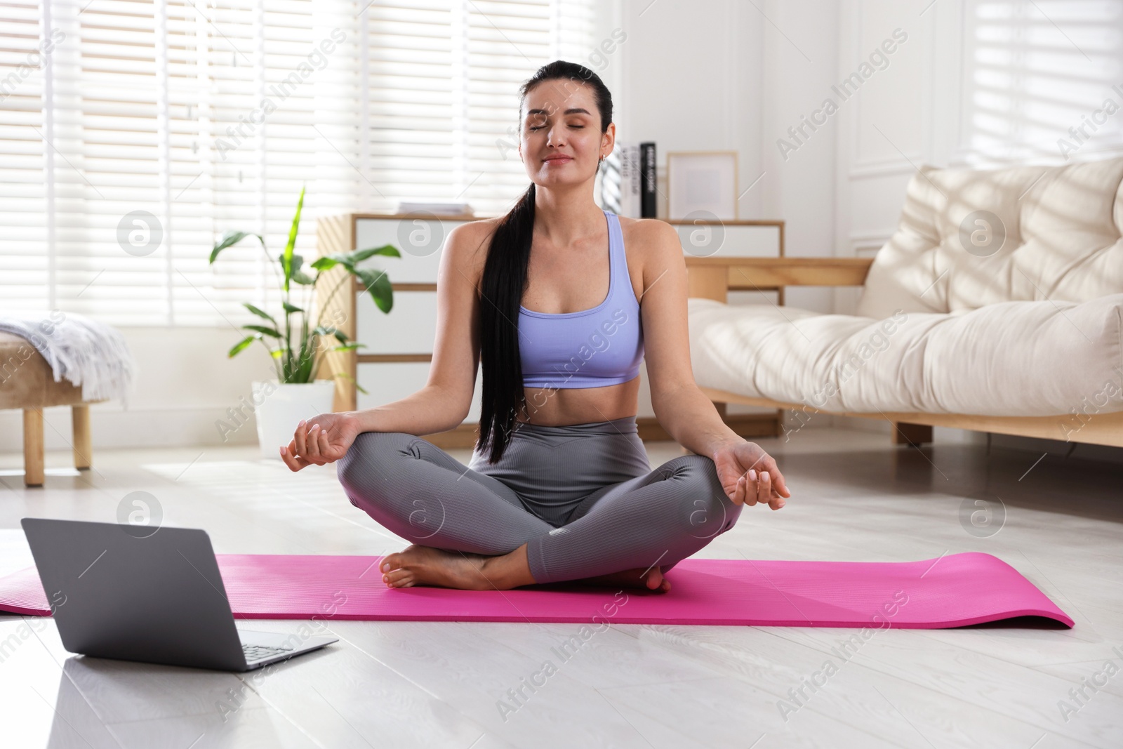 Photo of Woman with laptop meditating on floor at home