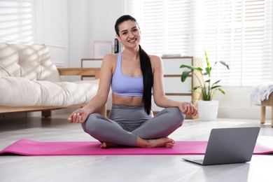 Photo of Woman with laptop meditating on floor at home