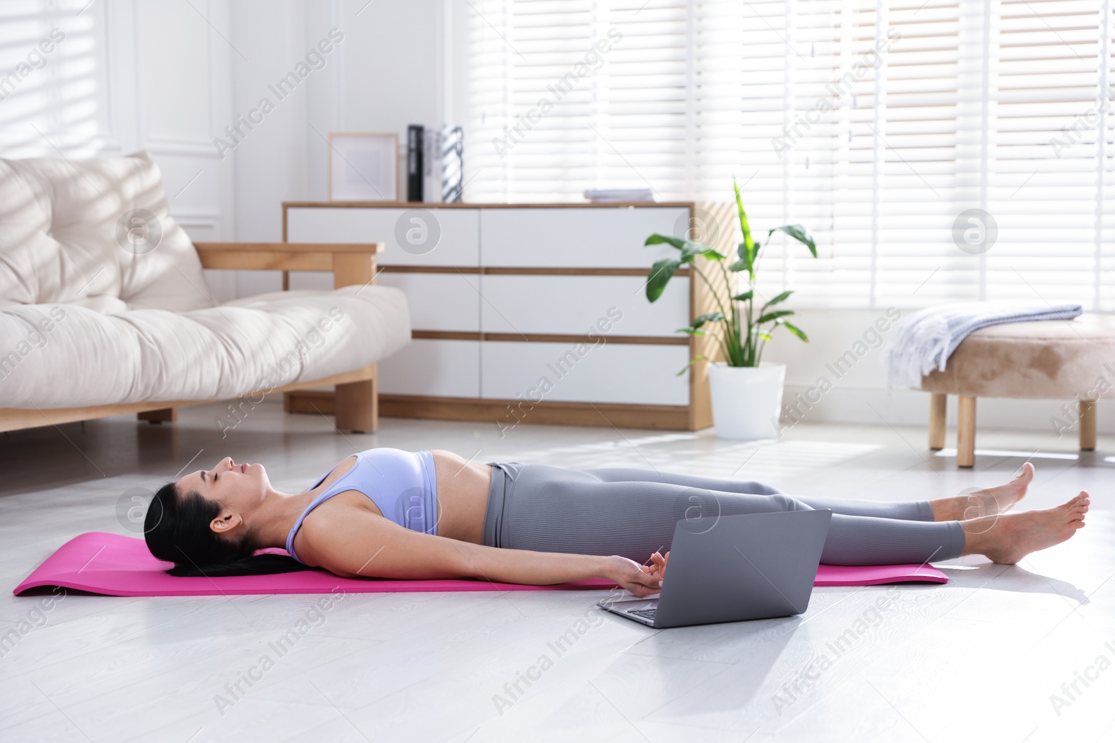 Photo of Woman with laptop meditating on floor at home