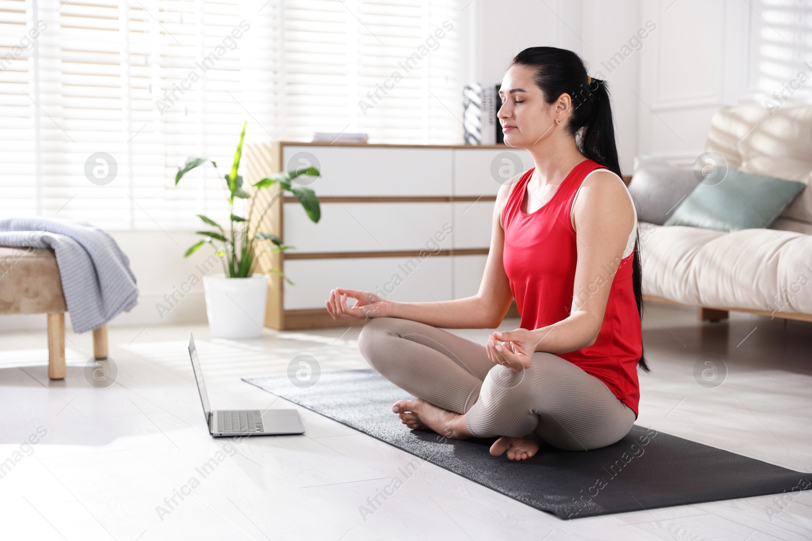 Photo of Woman with laptop meditating on floor at home. Space for text