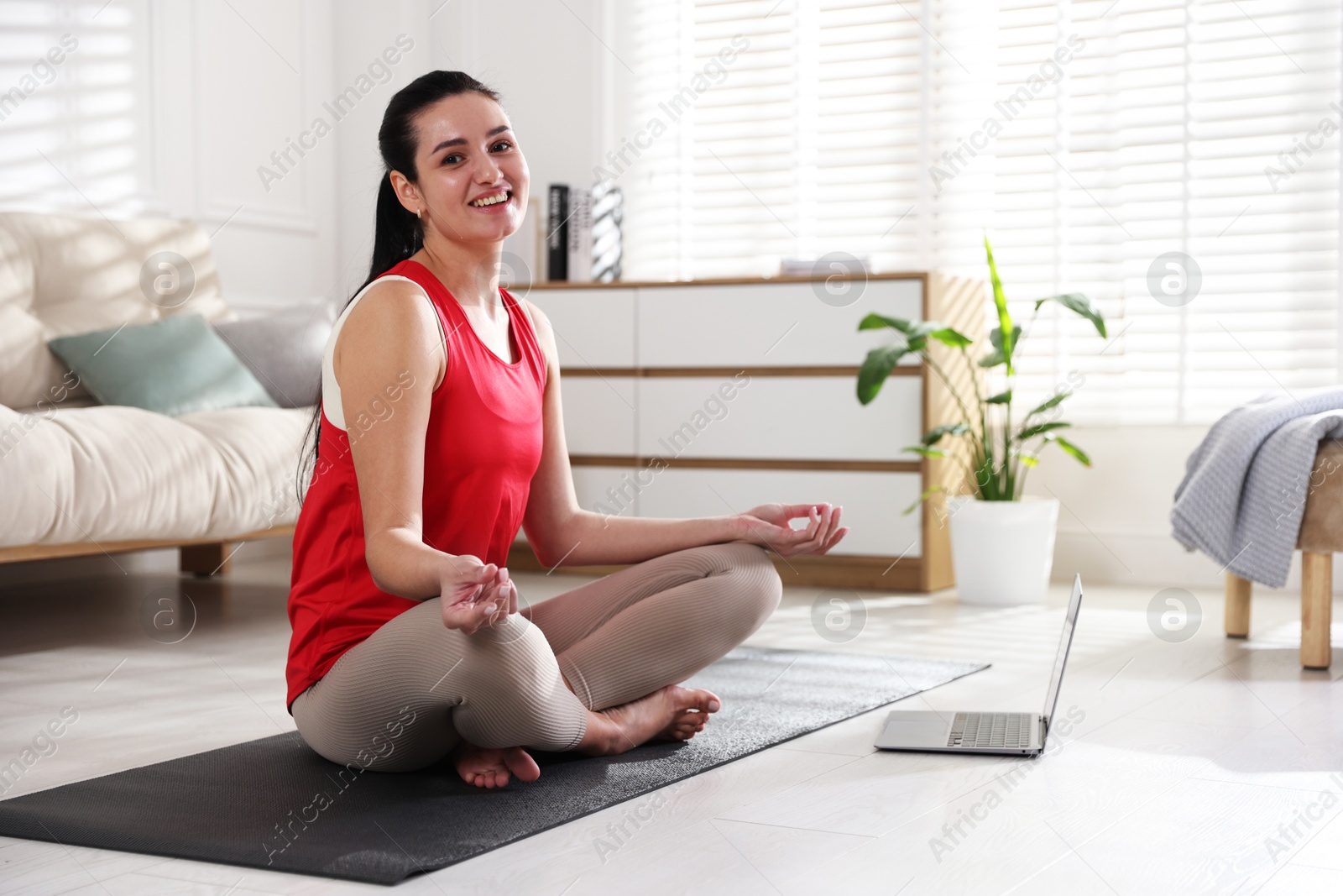 Photo of Woman with laptop meditating on floor at home. Space for text