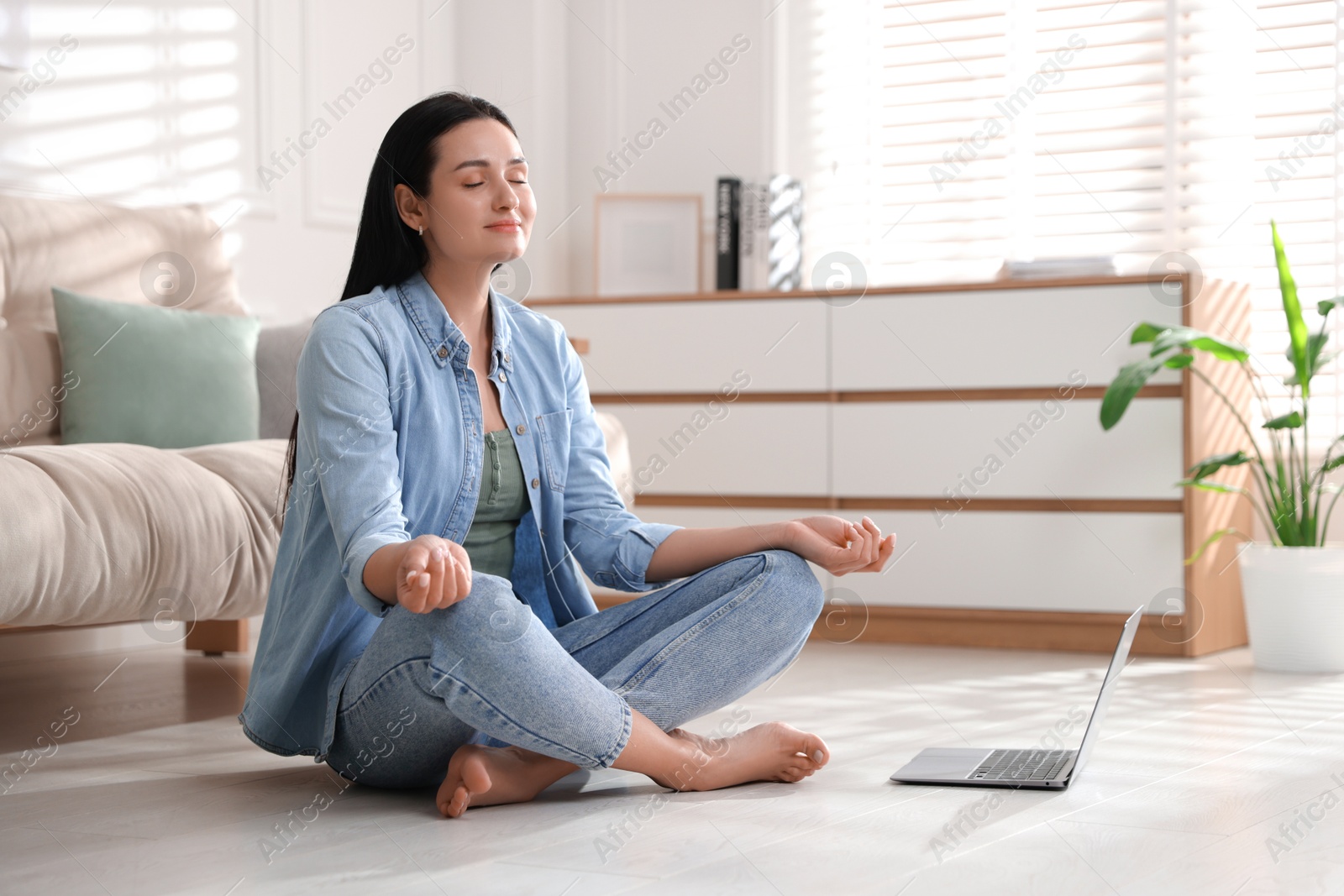 Photo of Woman with laptop meditating on floor at home. Space for text