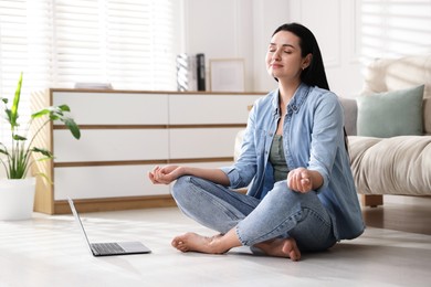 Photo of Woman with laptop meditating on floor at home. Space for text