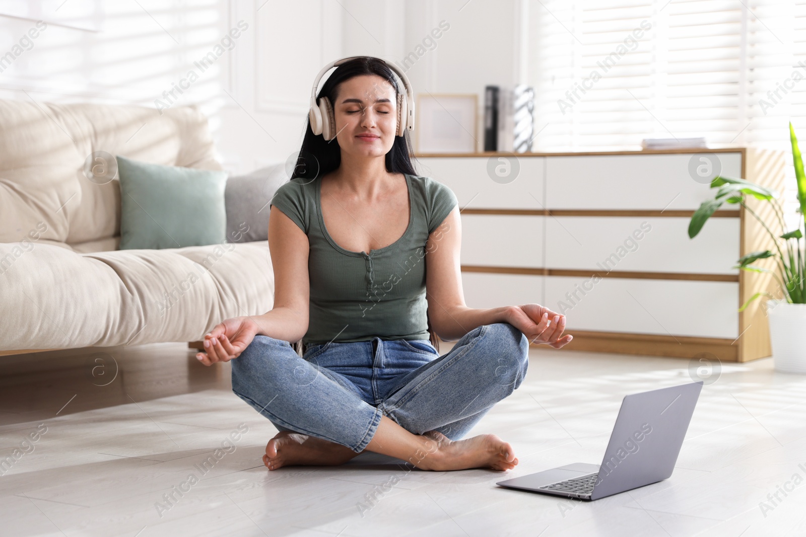 Photo of Woman with laptop meditating on floor at home