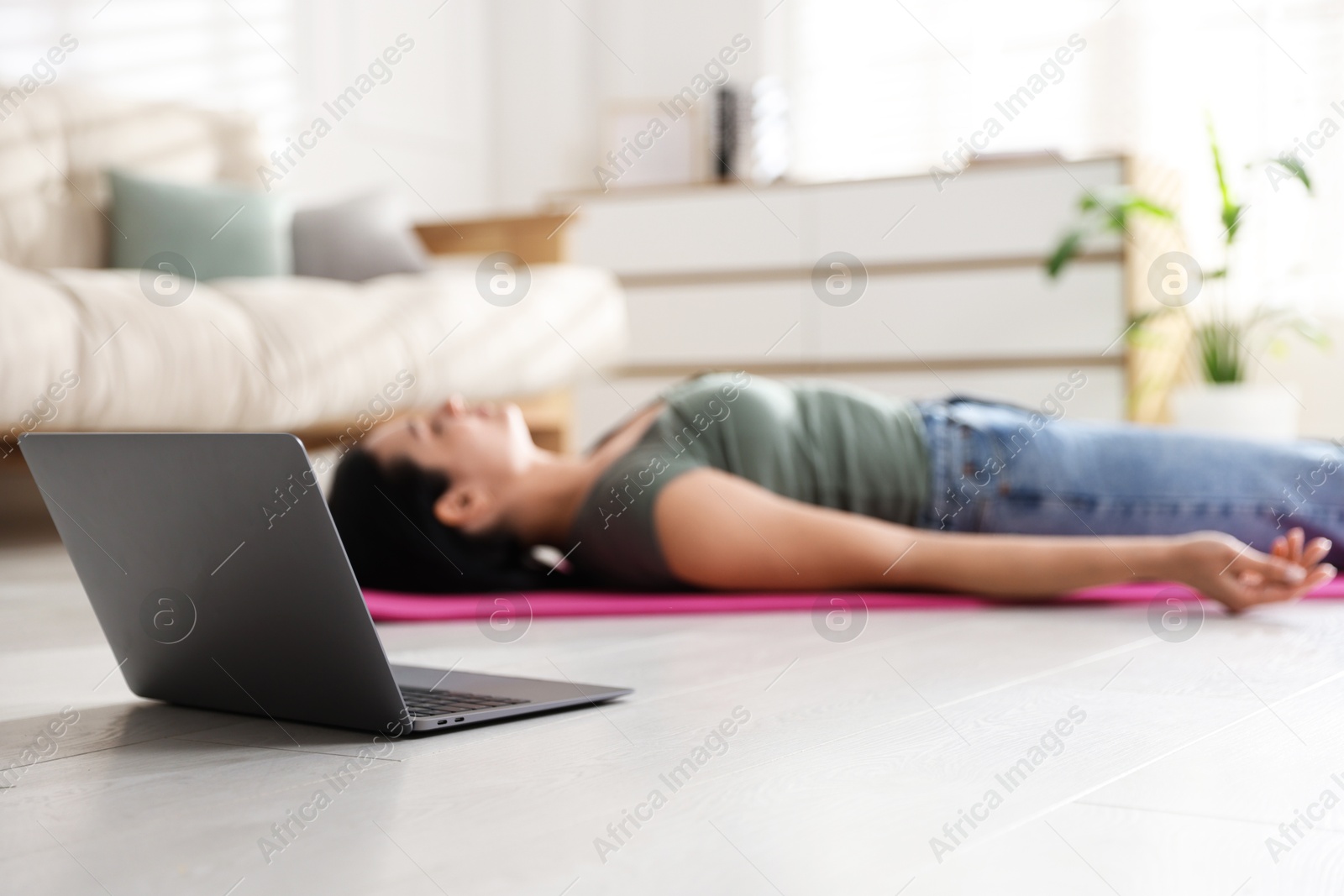 Photo of Woman with laptop meditating on floor at home, selective focus