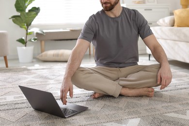 Meditation. Man watching video tutorial by laptop on floor at home, closeup