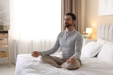 Photo of Handsome man meditating on bed at home