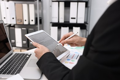 Photo of Electronic signature. Man using stylus and tablet at table indoors, closeup