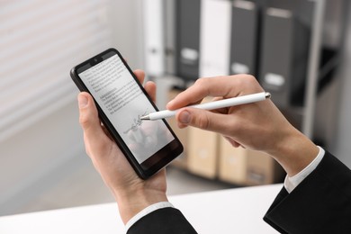 Photo of Electronic signature. Man using stylus and smartphone at table indoors, closeup