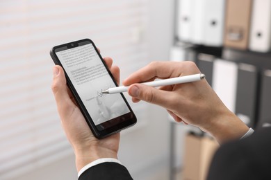 Photo of Electronic signature. Man using stylus and smartphone indoors, closeup