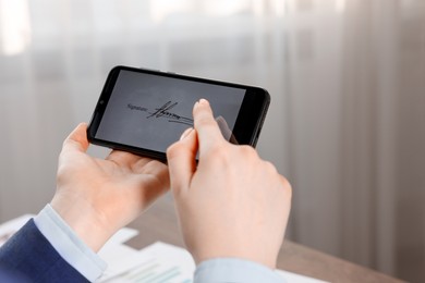 Photo of Electronic signature. Woman using smartphone indoors, closeup