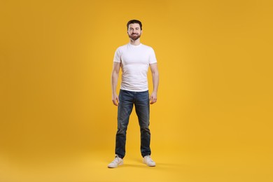 Photo of Man wearing blank white t-shirt on orange background. Mockup for design