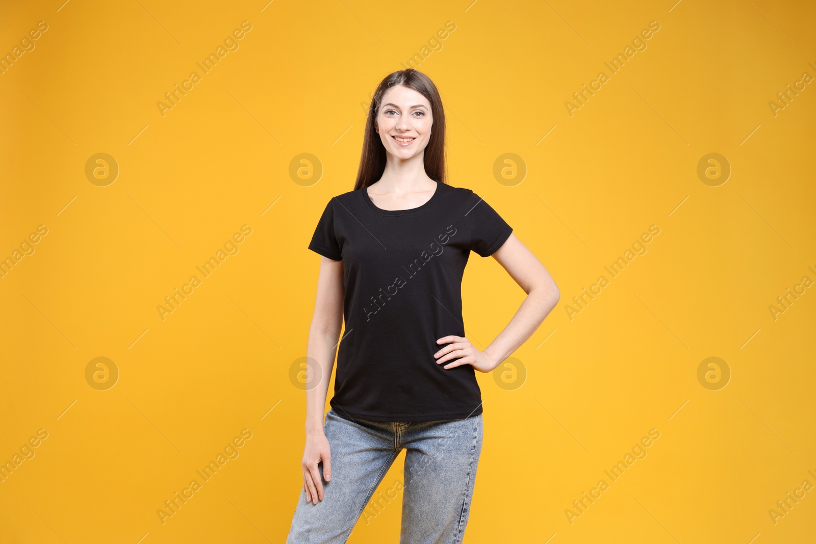 Photo of Woman wearing blank black t-shirt on orange background. Mockup for design