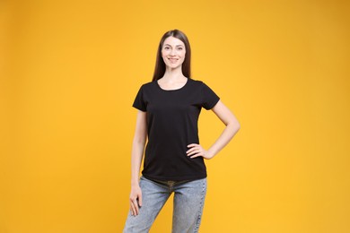 Photo of Woman wearing blank black t-shirt on orange background. Mockup for design