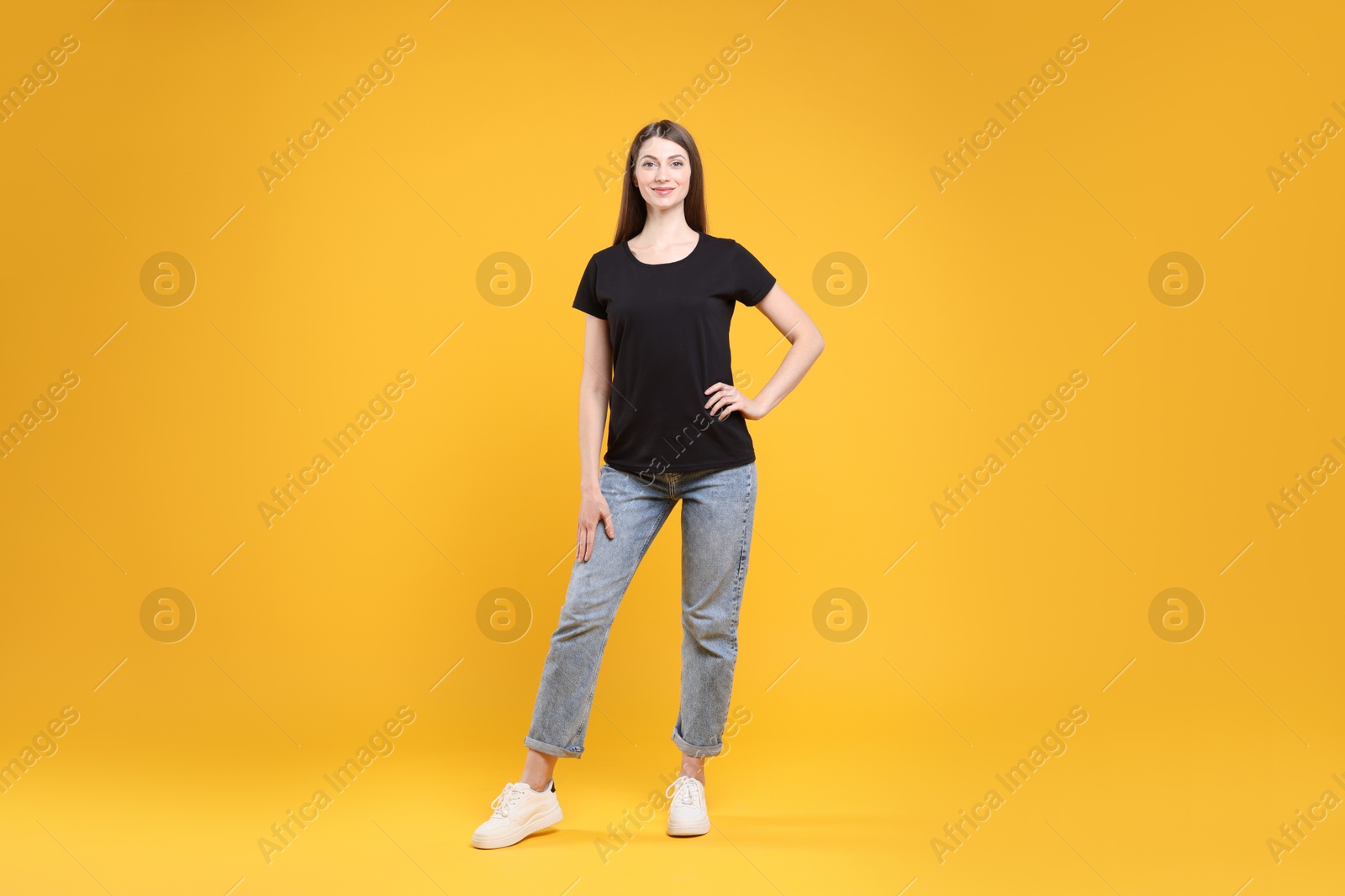 Photo of Woman wearing blank black t-shirt on orange background. Mockup for design