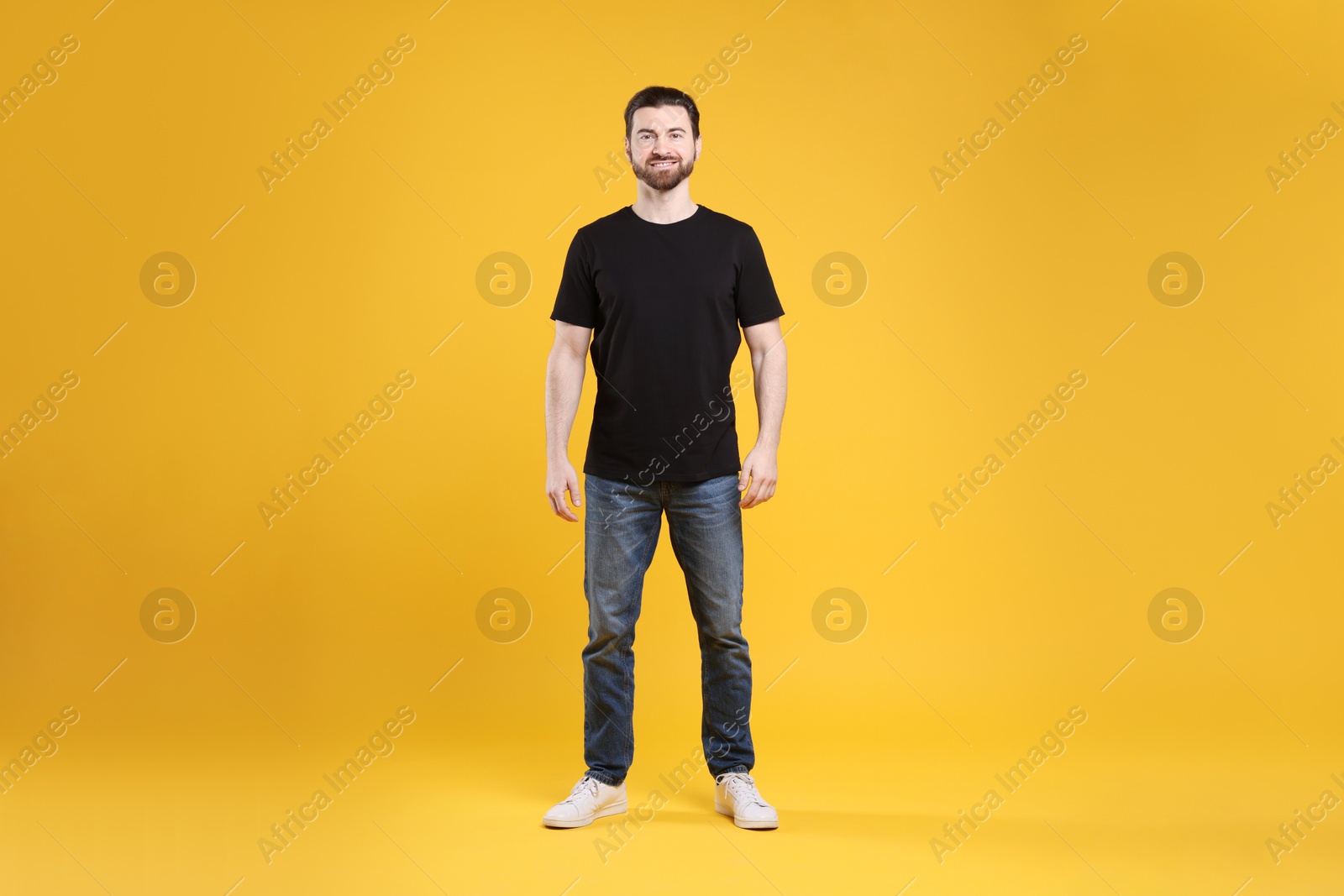 Photo of Man wearing blank black t-shirt on orange background. Mockup for design