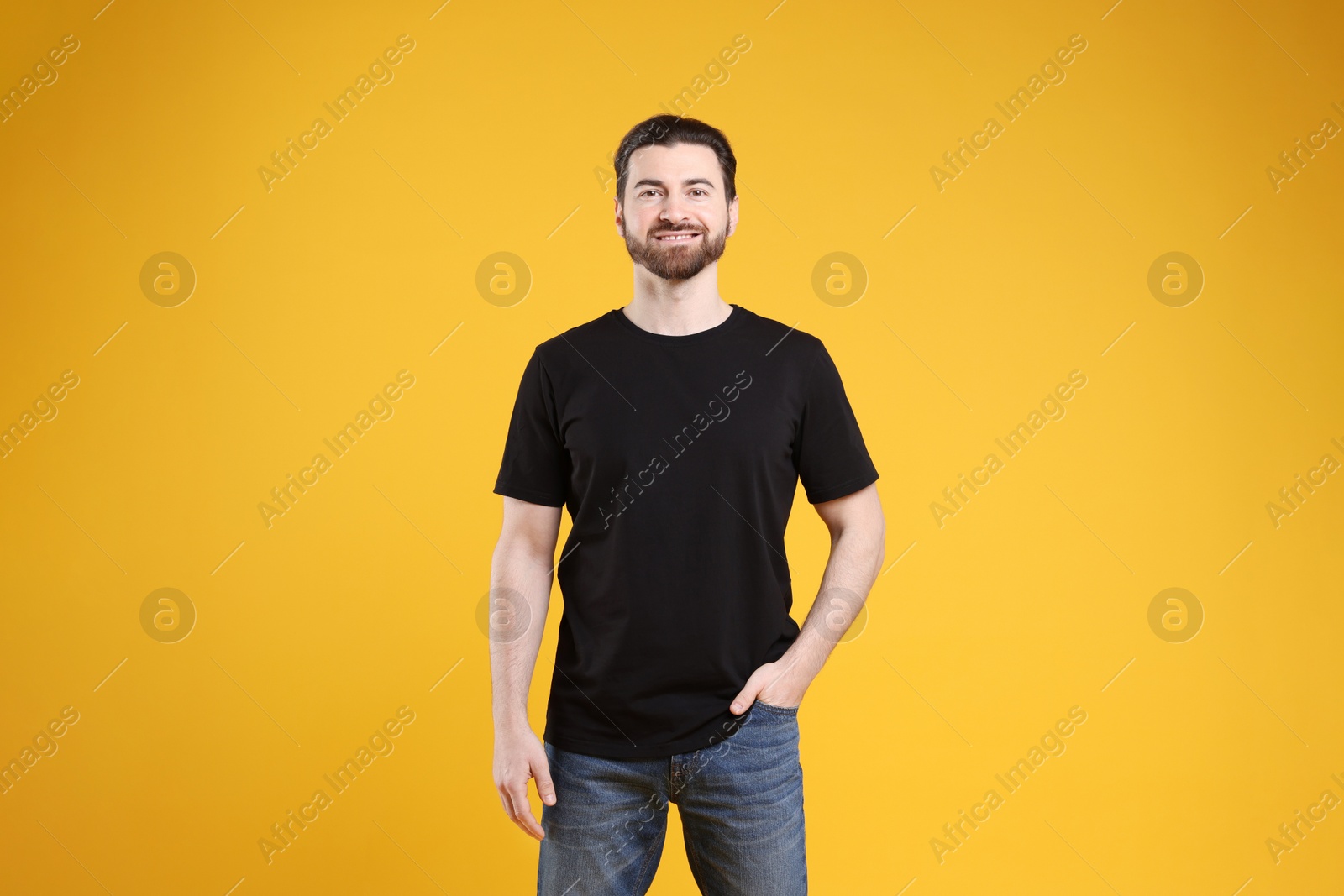 Photo of Man wearing blank black t-shirt on orange background. Mockup for design