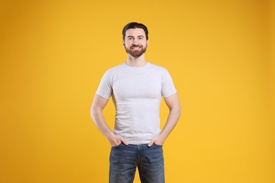 Photo of Man wearing blank white t-shirt on orange background. Mockup for design