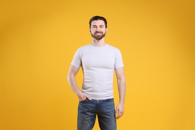 Man wearing blank white t-shirt on orange background. Mockup for design