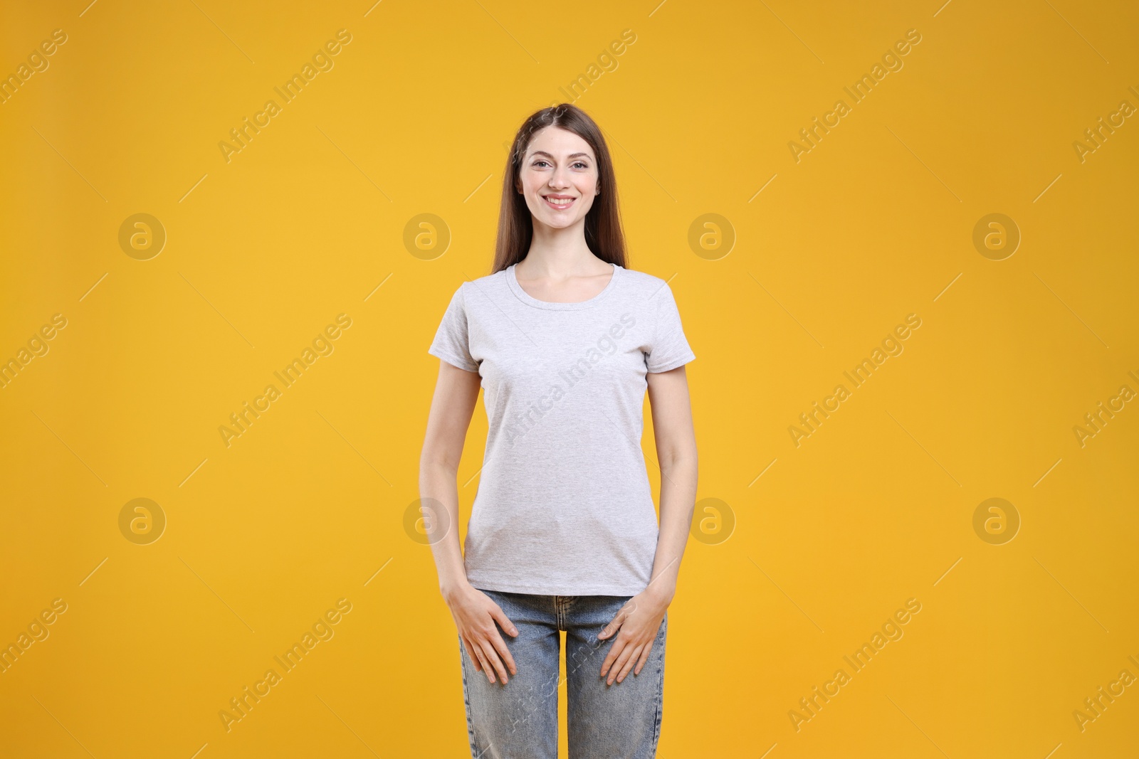 Photo of Woman wearing blank white t-shirt on orange background. Mockup for design