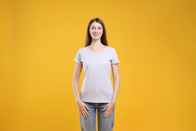 Photo of Woman wearing blank white t-shirt on orange background. Mockup for design