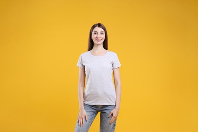 Photo of Woman wearing blank white t-shirt on orange background. Mockup for design