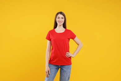 Photo of Woman wearing blank red t-shirt on orange background. Mockup for design