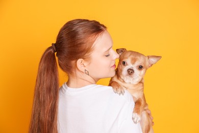 Photo of Teenage girl with her cute Chihuahua dog on yellow background