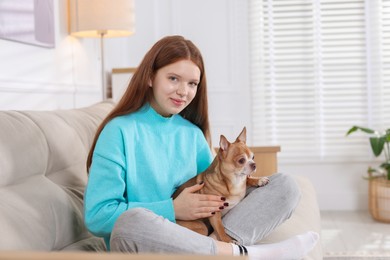 Photo of Teenage girl with her cute Chihuahua dog on sofa at home. Space for text