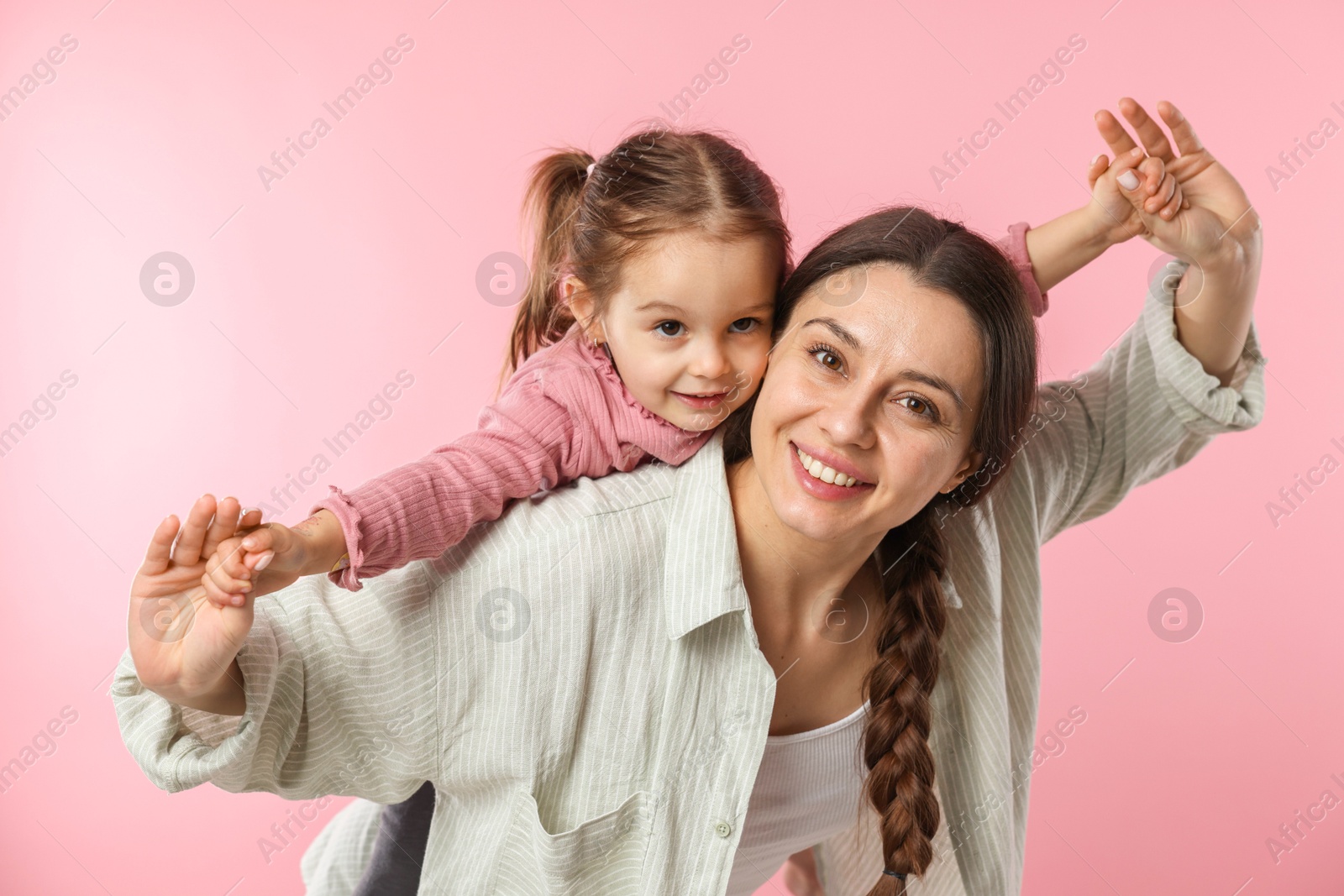 Photo of Portrait of happy mother and her cute daughter on pink background