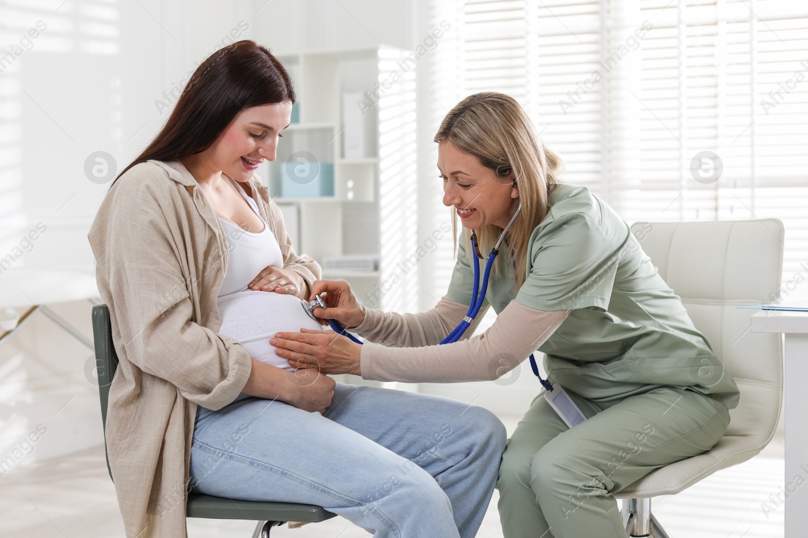 Photo of Pregnancy checkup. Doctor with stethoscope listening baby's heartbeat in patient's tummy indoors