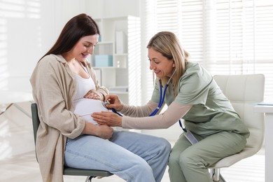 Photo of Pregnancy checkup. Doctor with stethoscope listening baby's heartbeat in patient's tummy indoors