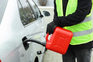 Photo of Man with canister refueling car outdoors, closeup