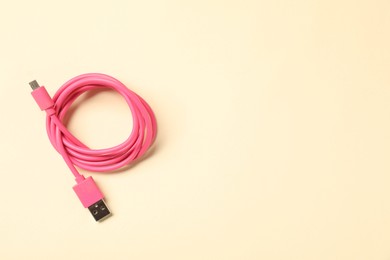 Photo of One USB charge cable on beige background, top view. Space for text