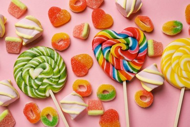 Many different tasty candies and marshmallows on pink background, flat lay