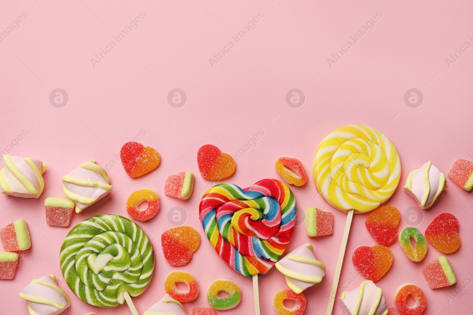 Photo of Many different tasty candies and marshmallows on pink background, flat lay. Space for text