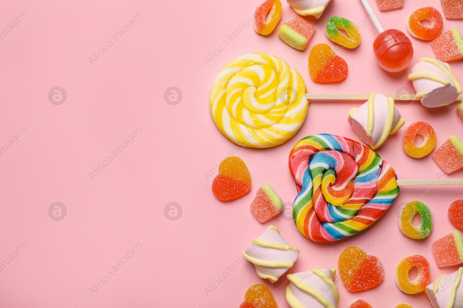 Photo of Many different tasty candies and marshmallows on pink background, flat lay. Space for text