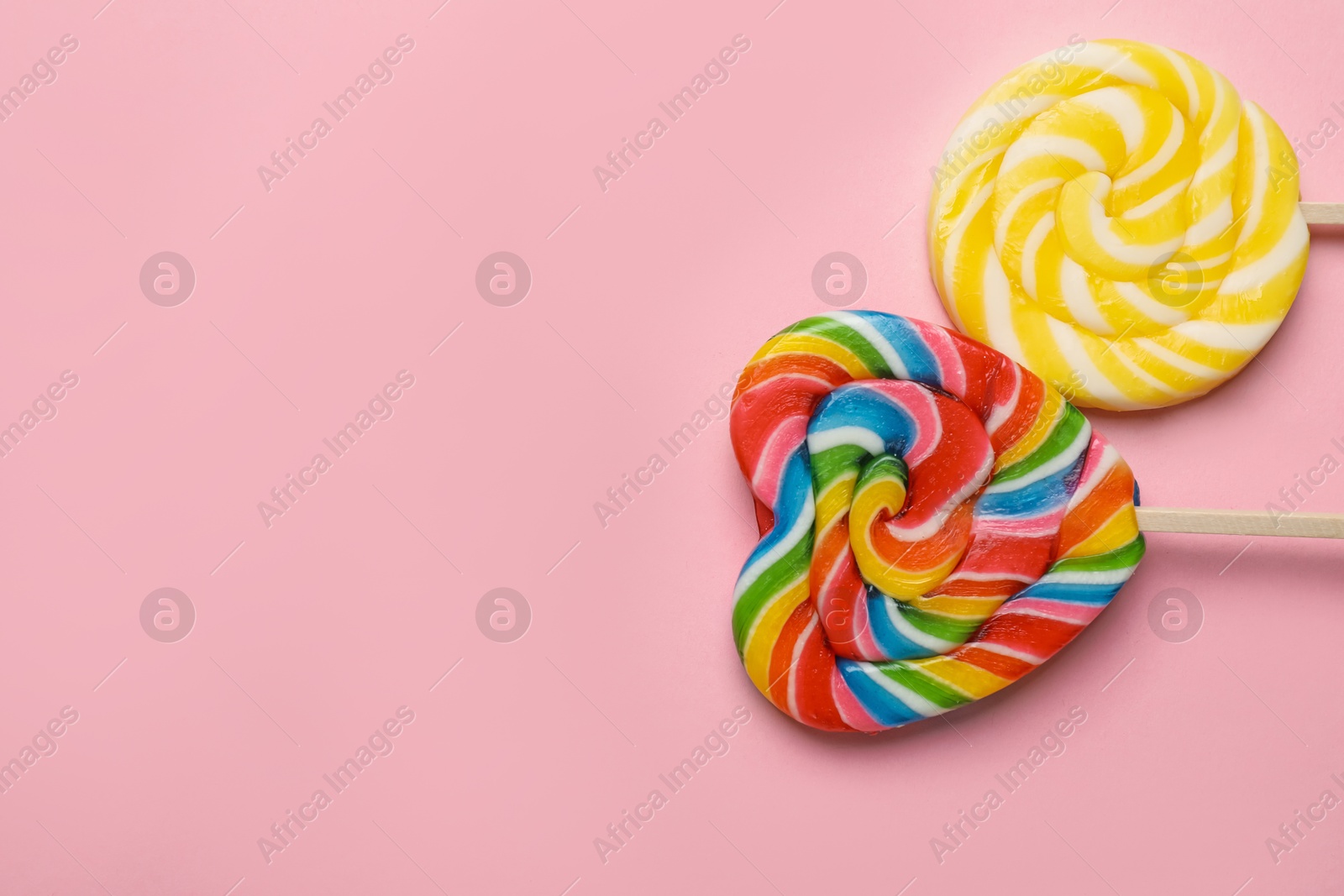 Photo of Tasty lollipops on pink background, flat lay. Space for text