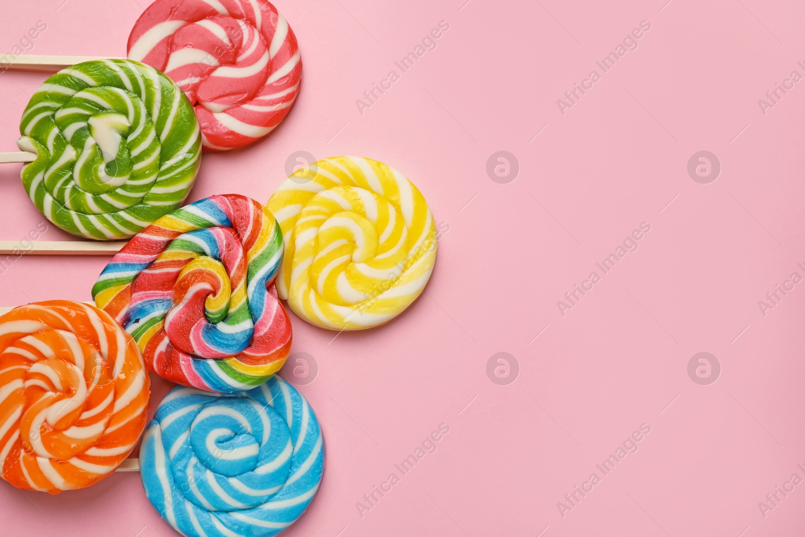 Photo of Tasty lollipops on pink background, flat lay. Space for text