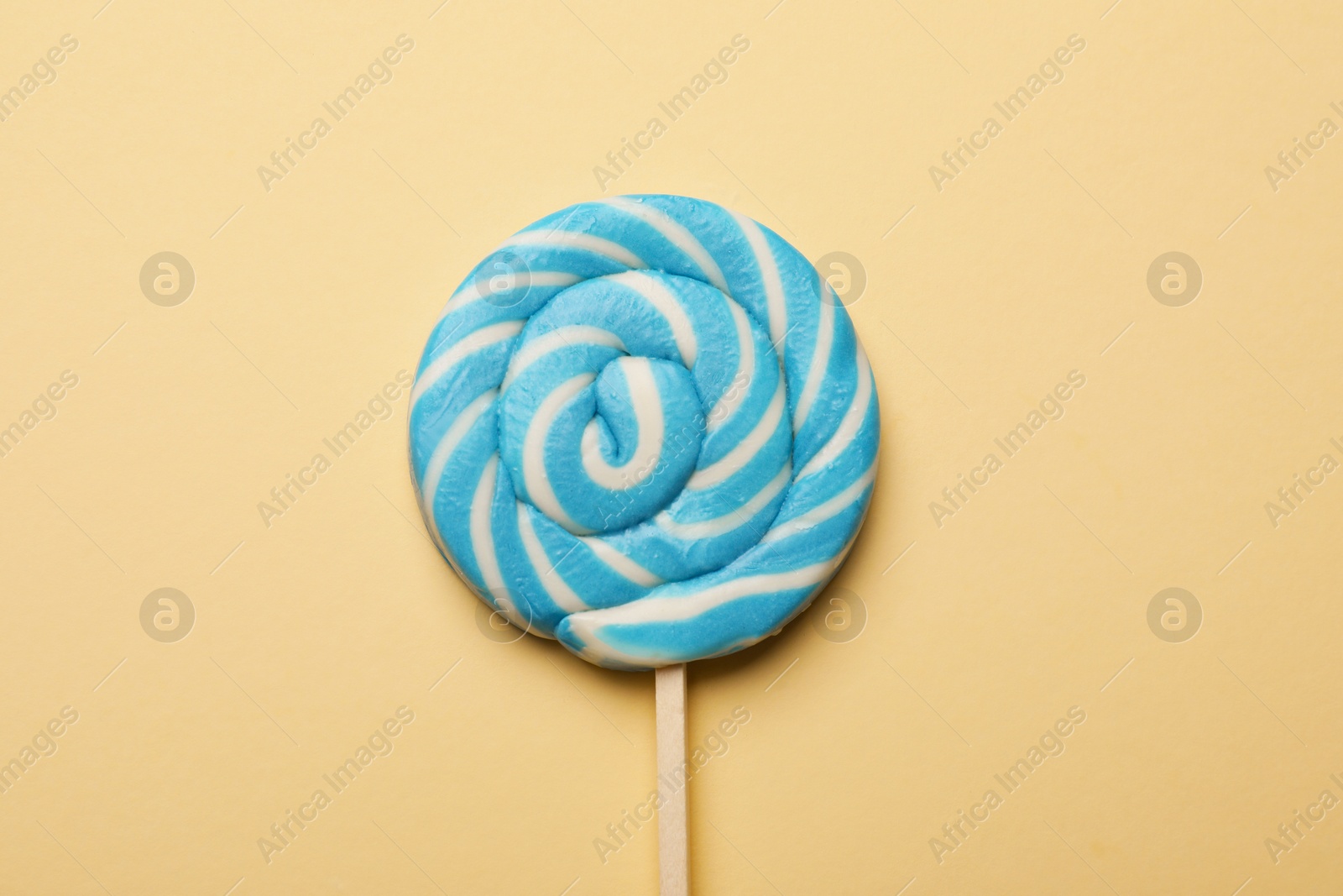 Photo of Tasty striped lollipop on beige background, top view