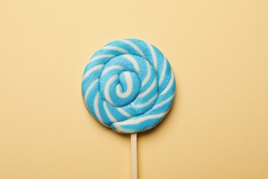 Tasty striped lollipop on beige background, top view