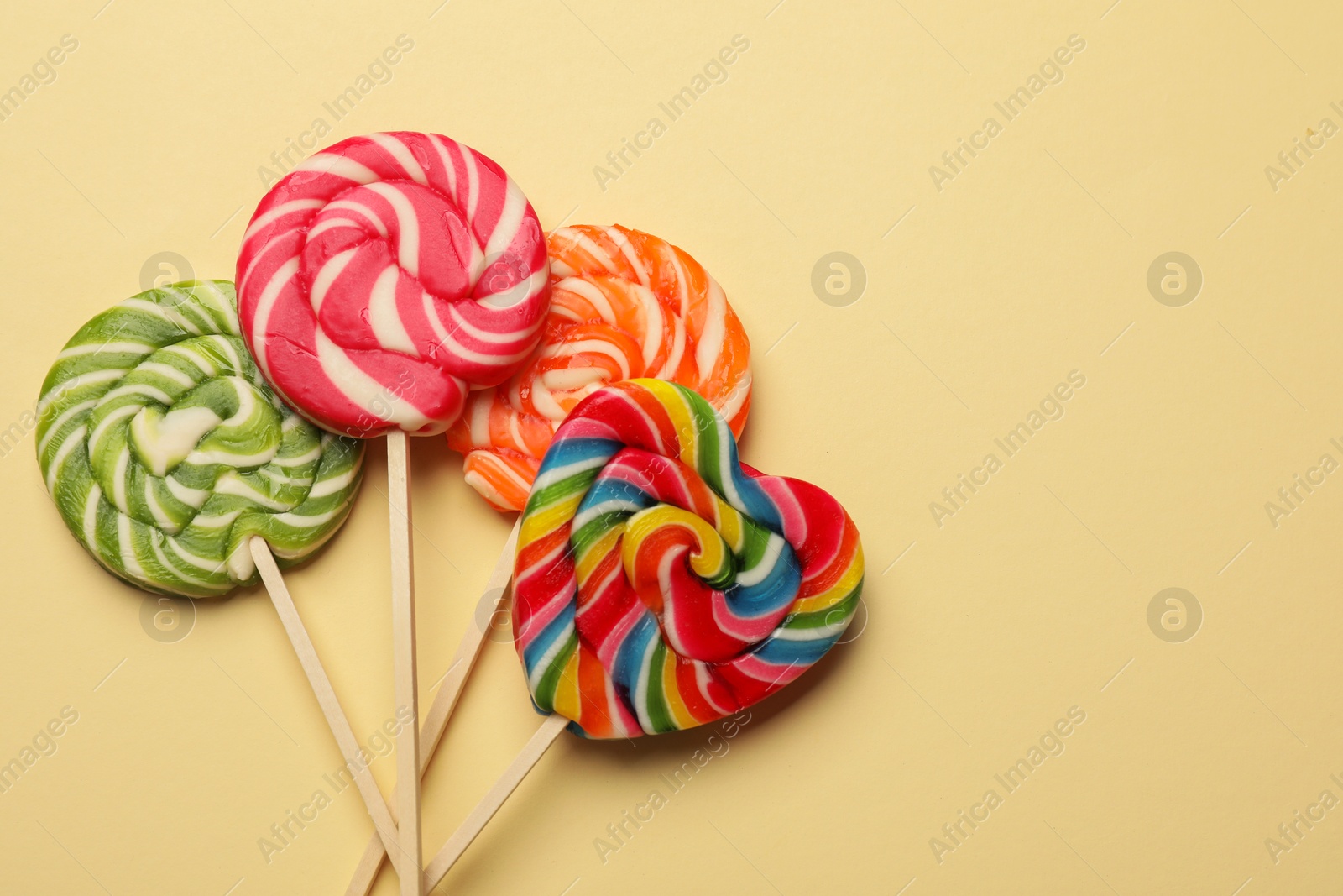 Photo of Tasty lollipops on beige background, flat lay. Space for text