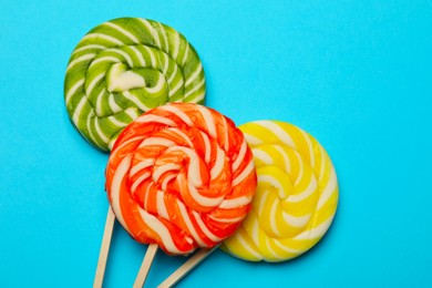 Tasty lollipops on light blue background, flat lay