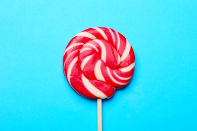 Tasty striped lollipop on light blue background, top view