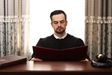 Photo of Judge with folder of documents at wooden table in courtroom