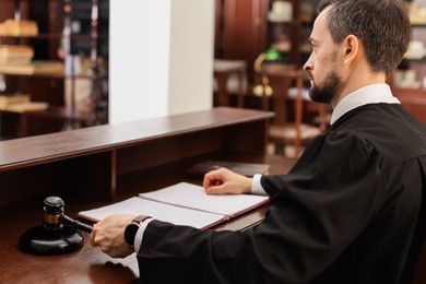 Photo of Judge striking gavel at wooden table in courtroom